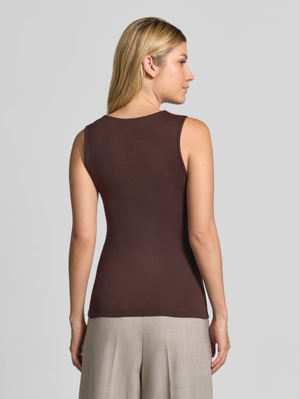 Vrouwenmodel draagt Regular Fit top uit viscosemix model 'ROSA' van VERO MODA in effen donkerbruin, rechte vormen en gladde textuur, dames top, geheellichaamsaanzicht achteraan.