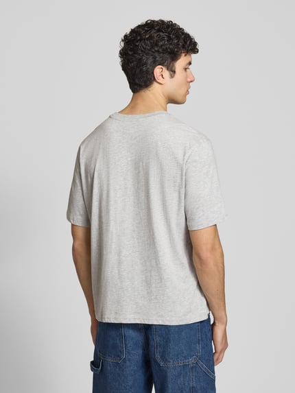 Männermodel trägt lichtgrijs T-shirt met logo en ronde hals van REVIEW, katoen- en viscosemix, regular fit, ruglengte maat M 64 cm, ganzkörperansicht rückansicht.