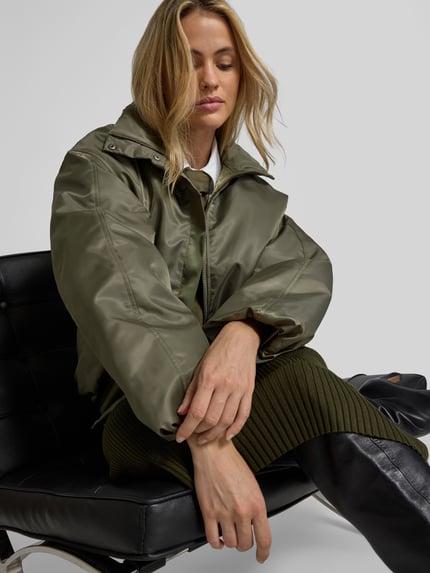Frauenmodel trägt Bomberjacke mit Stehkragen Modell 'CYRUS' von Anine Bing, Unifarbe, cropped, reine Baumwolle, Nahaufnahme Oberkörper.
