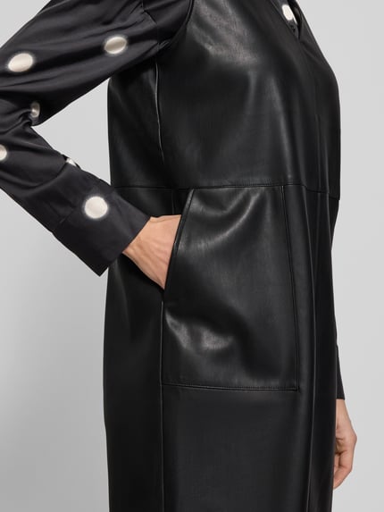Vrouwenmodel draagt knielang jurk in leerlook met V-hals, steekzakken, recht model, Model 'Wancy' van Opus, detailopname rechterzijde.