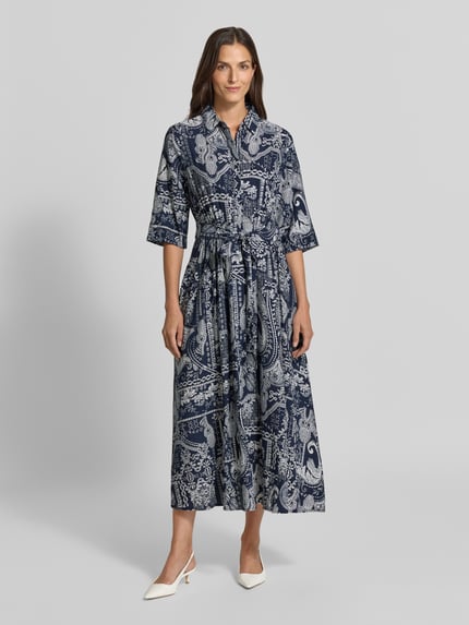 Frauenmodel trägt Hemdblusenkleid aus Viskose-Mix mit Bindegürtel von Christian Berg Woman, blau gemusterte A-Linie, Ganzkörperansicht von vorne.