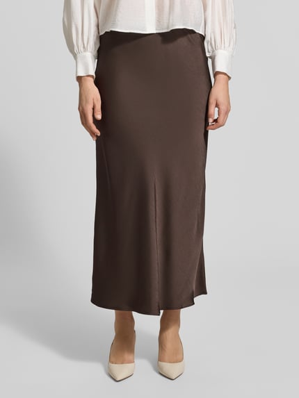 Frauenmodel trägt Maxirock aus Satin Modell 'Vicky' von Neo Noir in Dunkelbraun, elastischer Bund, körpernahe Passform, Nahaufnahme Unterkörper.
