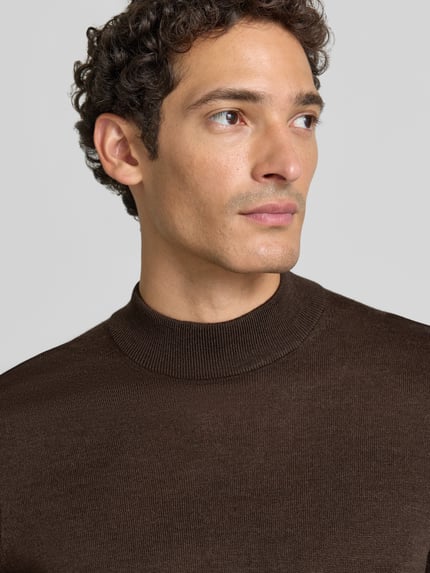 Męski model nosi Regular Fit Turtleneck aus Woll-Mix von Christian Berg Men, brązowa mieszanka wełny, prążkowane wykończenia, długi rękaw, długość tyłu 69 cm, długość rękawów 51 cm, detaliczny widok na górną część tułowia.
