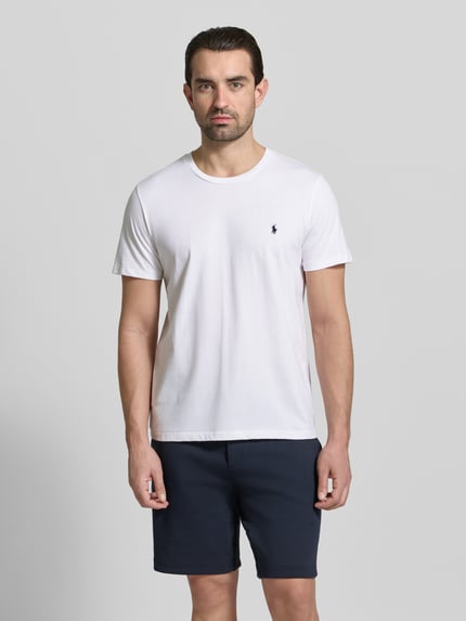 Männermodel trägt T-Shirt mit Logo-Stitching von Polo Ralph Lauren in Weiß, reine Baumwolle, gerade Passform, Rundhalsausschnitt, Ganzkörperansicht von vorne.