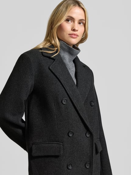 Modelka kobieca nosi Mantel aus Woll-Mix mit Reverskragen Modell 'Frannie' od My Essential Wardrobe w kolorze ciemnoszarym, wyraźna faktura, krój regular fit, patkowe kieszenie, podwójny rząd guzików, szerokość w rozmiarze 36: 51 cm, długość tyłu: 122 cm, szerokość ramion: 42 cm, długość rękawa: 63 cm, ujęcie z przodu, zbliżenie górnej części ciała
