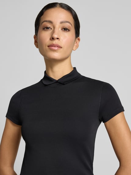 Kobiece modelka nosi Slim Fit T-Shirt mit hochschließendem Polokragen von Marc Cain z mieszanki bawełny i elastanu, krój slim fit, kołnierzyk polo, Rękaw o dł. 1/2, Długość tyłu w rozmiarze 36: 59 cm, zbliżenie na górną część ciała