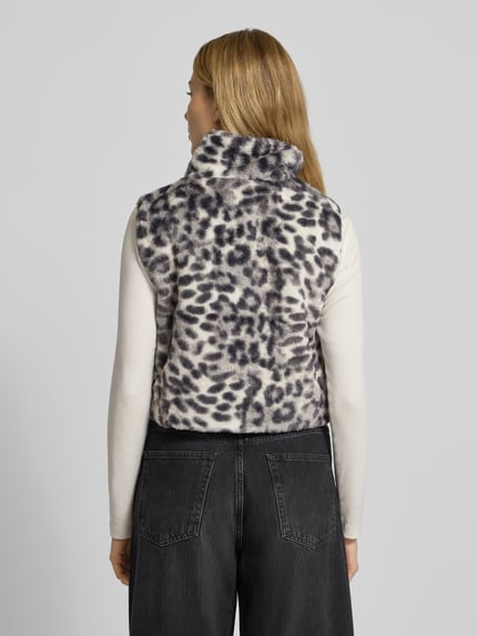 Vrouwenmodel draagt Weste uit imitatiebont met tweewegritssluiting van monari, regular fit, luipaardprint, opstaande kraag, ruglengte 44 cm, schouderbreedte 35 cm, borstwijdte 46 cm. Ganzkörperansicht Rückansicht.