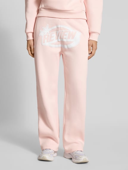 Vrouwenmodel draagt Straight Leg Sweatpants met Logo en elastische band van Review, katoenmix, straight fit, logoprint, detailopname voorkant.