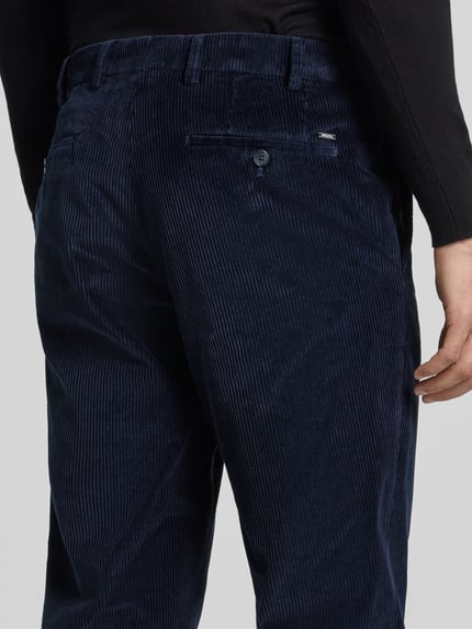 Männermodel trägt Regular Fit Cordhose aus Baumwollmix von Hiltl in Dunkelblau, feine Cordstruktur, Ganzkörperansicht Rückansicht.