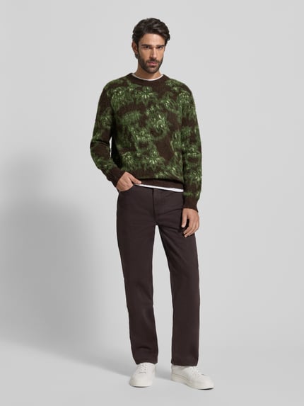 Männermodel trägt Strickpullover mit Rundhalsausschnitt Modell 'Herbert' von Wood Wood im Allover-Look, Material-Mix mit Alpaka-Anteil, Regular-Fit, melierte Grüntöne und braune Akzente, Rückenlänge 67 cm, Ärmellänge 67 cm, Ganzkörperansicht von vorne.