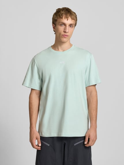 Männermodel trägt T-Shirt mit Logo-Stitching von The North Face in hellgrün, reine Baumwolle, gerader Schnitt, Nahaufnahme Oberkörper.