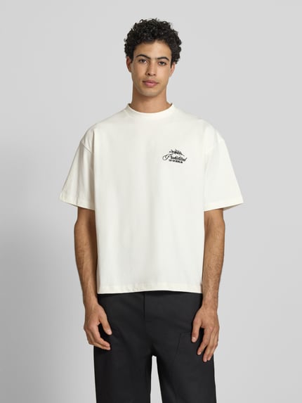 Männermodel trägt T-Shirt mit Label-Stitchings und Rundhalsausschnitt von PROHIBITED, Herren T-Shirt aus Reine Baumwolle, Regular-Fit, Rückenlänge 65 cm bei Größe M, helle Farbe, glatte Textur, Ganzkörperansicht von vorne.