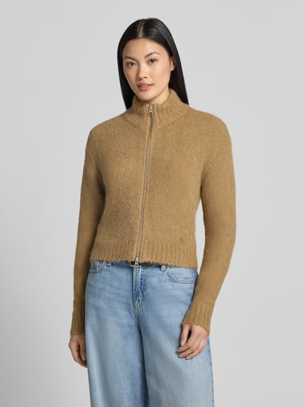 Frauenmodel trägt Regular Fit Jacke aus Alpaka-Mix Modell 'Jeanne' von Samsøe Samsøe, beigefarbene Strick-Optik, Stehkragen, Zweiwege-Reißverschluss, Ganzkörperansicht von vorne.