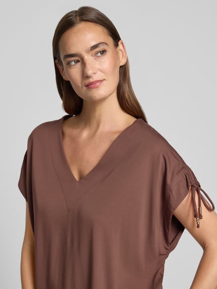 Modelka kobieca nosi Loose Fit T-Shirt aus Viskose-Mix von s.Oliver BLACK LABEL w kolorze brązowym, gładka tekstura, zbliżenie na górną część ciała, ujęcie z przodu.