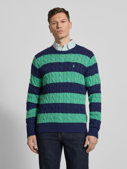 Männermodel trägt Regular Fit Strickpullover aus reiner Baumwolle von Polo Ralph Lauren in Two-Tone, Zopfmuster, Optik: Unifarben, Strickoptik, Logo-Detail, Rundhals, Langarm, Ärmel- und Rumpfabschluss gerippt, Ganzkörperansicht von vorne.