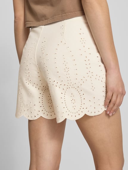 Frauenmodel trägt Regular Fit Shorts aus reiner Baumwolle Modell 'ELSA' von Only in Creme mit Lochstickmuster und Muschelsaum, Ganzkörperansicht Rückansicht.