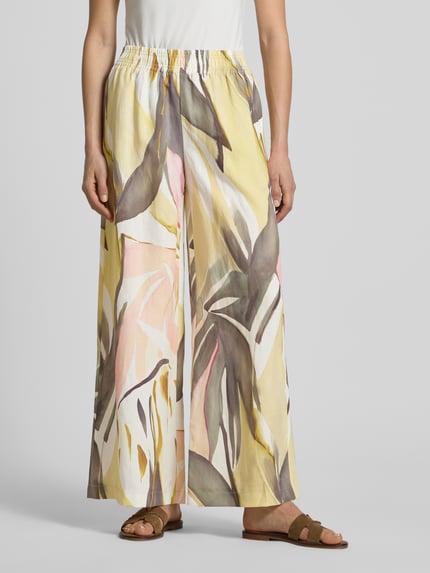 Frauenmodel trägt Wide Leg Stoffhose im Allover-Look Modell 'LIZETT' von Raffaello Rossi in Gelb mit abstraktem Muster, elastischer Bund, Ganzkörperansicht von vorne, Damen Stoffhose, Bundweite bei Größe 36: 40 cm, Innenbeinlänge bei Größe 36: 74 cm.