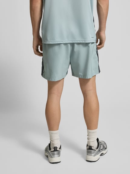 Męski model nosi Shorts mit elastischem Bund von adidas Training, kolor jasnoniebieski, czarne paski, krój regular fit, Szerokość w rozmiarze M: 39 cm, długość nogawki: 14 cm, widok całej sylwetki z tyłu