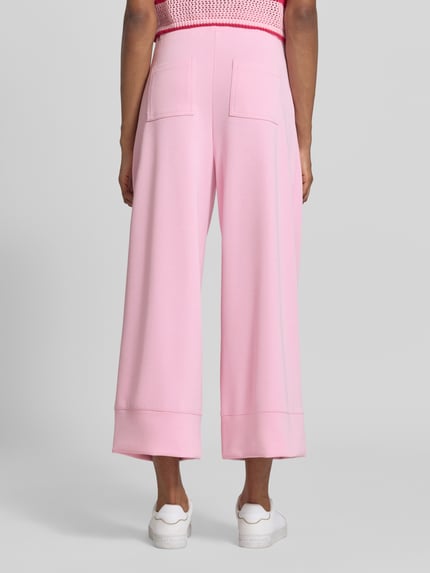 Frauenmodel trägt Wide Leg Sweatpants aus Modal-Mix von Rich & Royal in Rosa mit ausgestelltem Bein, Bundfalten und Gesäßtaschen, Ganzkörperansicht Rückansicht.