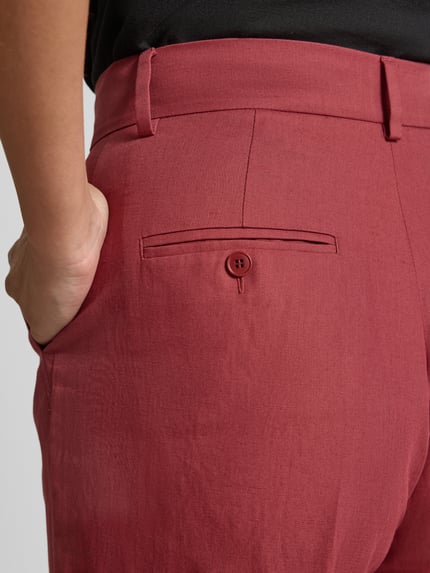 Kobieta nosi Regular Fit Leinenhose aus Baumwoll-Leinen-Mix Modell 'ZIRCONE' od Weekend Max Mara, efekt: jednolity kolor, mieszanka bawełny i lnu, wpuszczane kieszenie, szlufki na pasek, detal z guzikiem z tyłu, krój regular fit, widok na detal z boku, zdjęcie zbliżeniowe na biodra.
