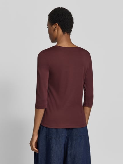 Frauenmodel trägt Shirt aus reiner Baumwolle von Christian Berg Woman in dunklem Rotbraun, glatte Textur, Ganzkörperansicht Rückansicht. Rückenlänge bei Größe 36: 59 cm, gerader Schnitt, Rundhalsausschnitt, halbärmeliges Design.