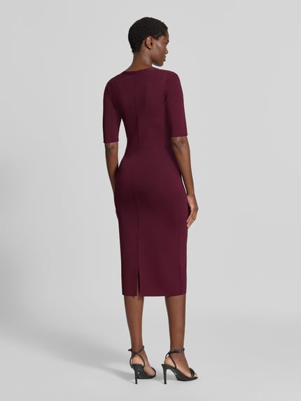 Frauenmodel trägt figurbetontes Etuikleid aus Viskose-Mix von Jake*s aus der Jake*s Collection in dunklem Bordeauxrot, Ganzkörperansicht Rückansicht.