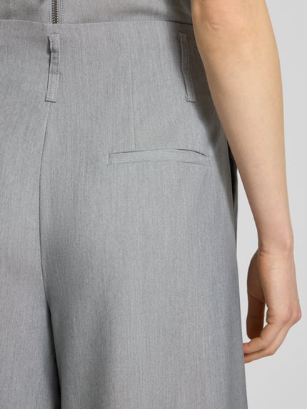 Frauenmodel trägt Stoffhose mit französischen Eingrifftaschen Modell 'Hanna' von My Essential Wardrobe, hellgrauer Material-Mix mit Viskose-Anteil, angedeutete Gesäßleistentasche, High Wide Fit, Haken- und Reißverschluss, Detailaufnahme Rückansicht. Bundweite bei Größe 36: 38 cm, Innenbeinlänge 79 cm.