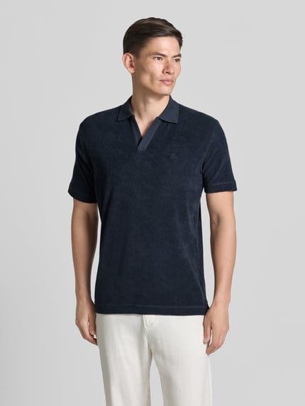 Mężczyznamodel nosi ciemnogranatową koszulkę polo Regular Fit Poloshirt aus reinem Baumwoll-Frottee von Marc O'Polo, gładka tekstura froty, Ganzkörperansicht von vorne.