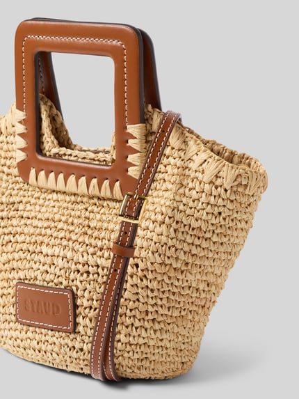 Produktfoto, Shoulder Bag in Flecht-Optik Modell 'Harlow' von Staud, naturfarbene Korbstruktur, eckige braune Schulterriemen, Detailaufnahme, Magnetverschluss, Maße 26x18x10 cm, Riemenlänge 113 cm.