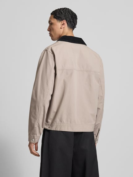 Männermodel trägt Regular Fit Ranch-Jacke aus reiner Baumwolle von Tommy Jeans in Beige mit Cordkragen und Logo-Stitching, Ganzkörperansicht Rückansicht.