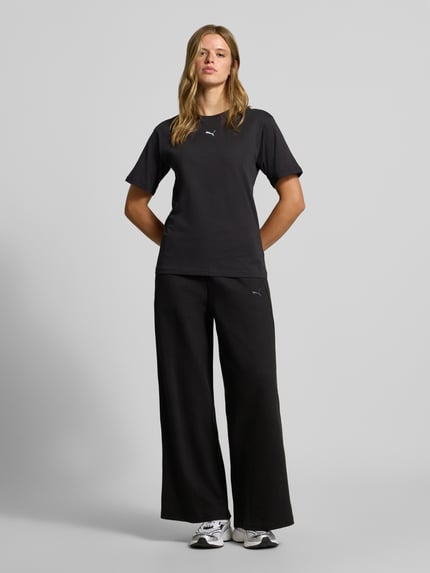 Frauenmodel trägt Relaxed Fit Sweathose aus reiner Baumwolle von PUMA, schwarze Farbe, weite Form, strukturierte Textur, Ganzkörperansicht von vorne, Damen Sweathose von PUMA.