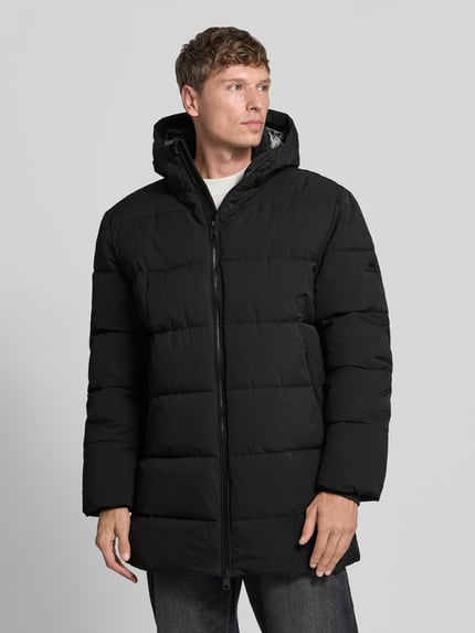 Männermodel trägt schwarzen Steppmantel mit Zweiwege-Reißverschluss Modell 'COMFORT' von CINQUE, glatte Struktur, Ganzkörperansicht von vorne. Herren Steppmantel, Straight Fit, Kapuze, Label-Patch, seitliche Reißverschlusstaschen, gerippte Ärmelabschlüsse, Maße bei Größe M: Rückenlänge 88 cm, Schulterbreite 52 cm, Brustweite 64 cm, Ärmellänge 69 cm.