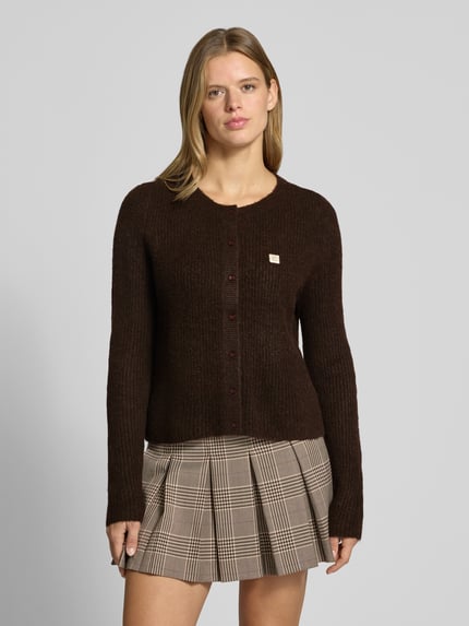Frauenmodel trägt Cardigan mit Label-Patch von ONLY in Dunkelbraun, Strickoptik, Knopfleiste, gerippte Abschlüsse, Nahaufnahme Oberkörper.