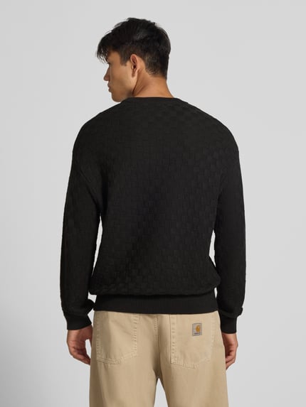 Männermodel trägt Regular Fit Strickpullover aus reiner Baumwolle mit Label-Detail von REVIEW, dezentes Karo-Muster, Elastikabschlüsse, Ganzkörperansicht Rückansicht.