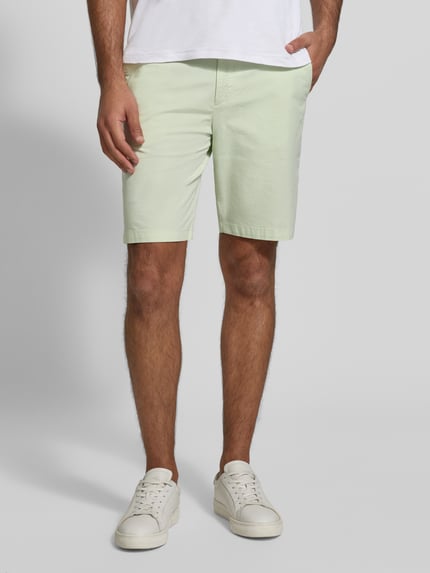Männermodel trägt Tapered Chinoshorts aus Baumwoll-Mix Modell 'CHINO_TAPERED_DS_3S' von BOSS Orange in Hellgrün, Ganzkörperansicht von vorne. Herren Chinoshorts, unifarben, elastischer Bund, seitliche Eingrifftaschen, BOSS Label Patch, Knopfverschluss.