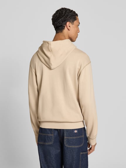 Männermodel trägt Regular Fit Hoodie aus reiner Baumwolle von G-Star RAW in Beige, strukturierte Oberfläche, Ganzkörperansicht Rückansicht.
