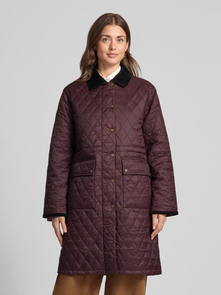Frauenmodel trägt Regular Fit Steppmantel mit Druckknöpfen von Barbour in Dunkelrot mit schwarzem Kragen und Rautensteppung, Ganzkörperansicht von vorne. Damen Steppmantel von Barbour.