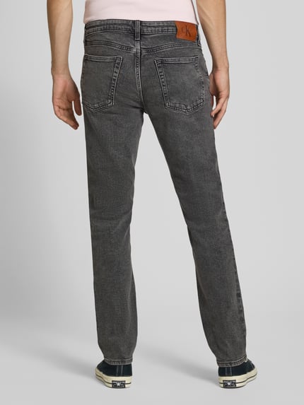 Mężczyzna nosi Slim Fit Jeans aus Baumwoll-Mix von Calvin Klein Jeans, szare odcienie, widoczne kieszenie, faktura denimu, całkowity widok z tyłu.