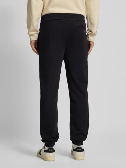 Männermodel trägt Oversized Jogginghose aus reiner Baumwolle Modell 'WEI_CNY' von BOSS in Unifarbe mit Label Print, Sweat-Textur, seitliche Eingrifftaschen, Ganzkörperansicht Rückansicht.