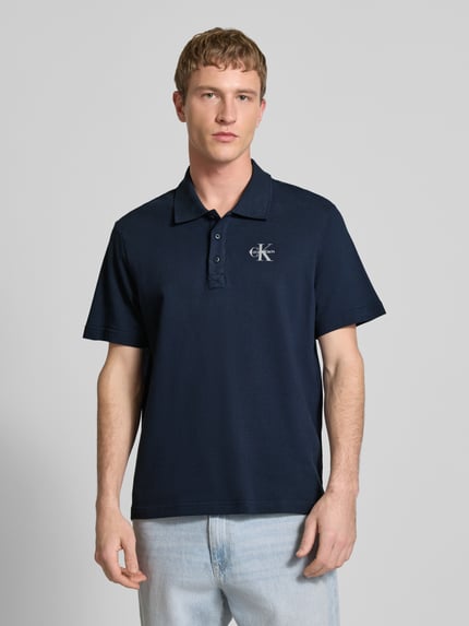 Männermodel trägt Easy Fit Poloshirt mit Polokragen von Calvin Klein Jeans, Reine Baumwolle, Label-Stitching, navyblau, Ganzkörperansicht von vorne.