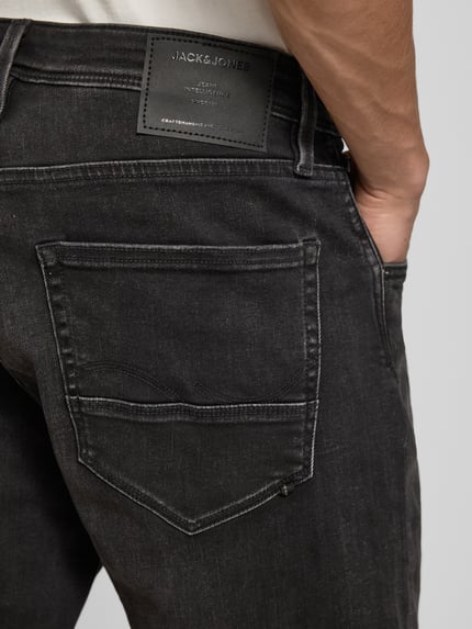 Männermodel trägt Jeansshorts mit Umschlag Modell 'RICK' von Jack & Jones aus schwarzem Baumwoll-Mix mit Stretch-Anteil, Detailaufnahme Rückansicht.