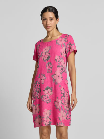 Frauenmodel trägt Leinenkleid in Minilänge Modell 'Miraa' von ZABAIONE in Pink mit Blumenmuster, leicht tailliert, Ganzkörperansicht von vorne.
