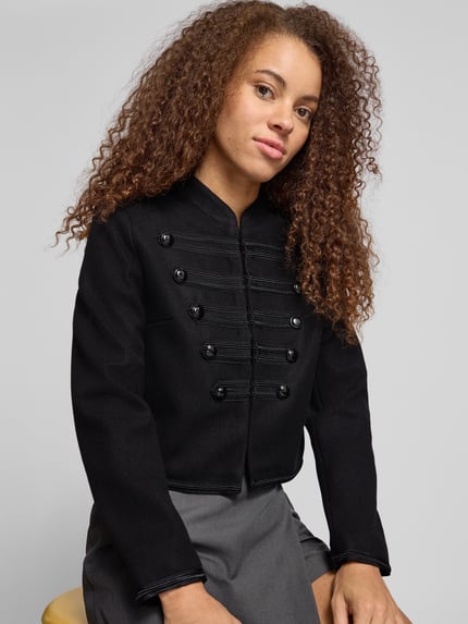 Frauenmodel trägt Blouson mit Uniform Zierknöpfen Modell 'ONLNANCY' von ONLY, unifarben schwarz, Stehkragen, Nahaufnahme Oberkörper.