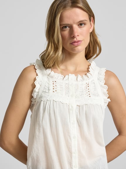 Frauenmodel trägt Blusentop mit Lochstickerei Modell 'SALMA' von Noisy May aus Reine Baumwolle, Karree-Ausschnitt, Knopfleiste, Loose-Fit, Nahaufnahme Oberkörper.
