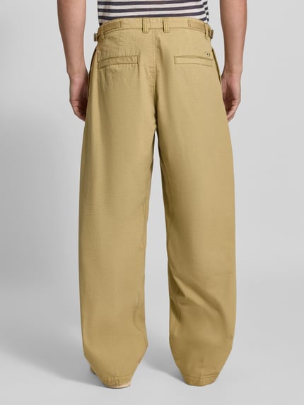 Männermodel trägt Straight Fit Hose aus reiner Baumwolle von Diesel in Beige mit Gesäßtaschen, Rückansicht, Ganzkörperansicht.