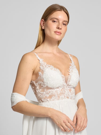 Frauenmodel trägt Abendkleid mit Spitze und V-Ausschnitt von Mascara in Weiß, Chiffon, A-Linie, Nahaufnahme Oberkörper.