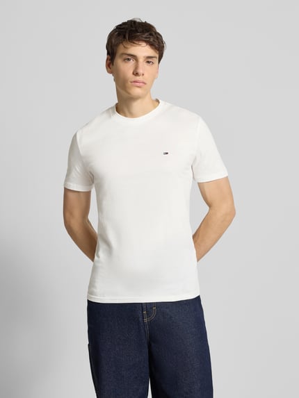 Männermodel draagt Slim Fit T-Shirt aus reiner Baumwolle im 2er-Pack van Tommy Jeans, wit, kort mouw, logo-detail, unikleur, Ganzkörperansicht von vorne.
