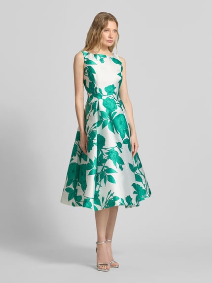 Vrouwenmodel draagt Cocktailjurk im Allover-Look van Adrianna Papell in wit en groen satijn, getailleerd model, midi-jurk, ronde hals, ruglengte maat 36: 110 cm, borstwijdte maat 36: 38 cm, all-over look, volledig lichaamsbeeld van voren.