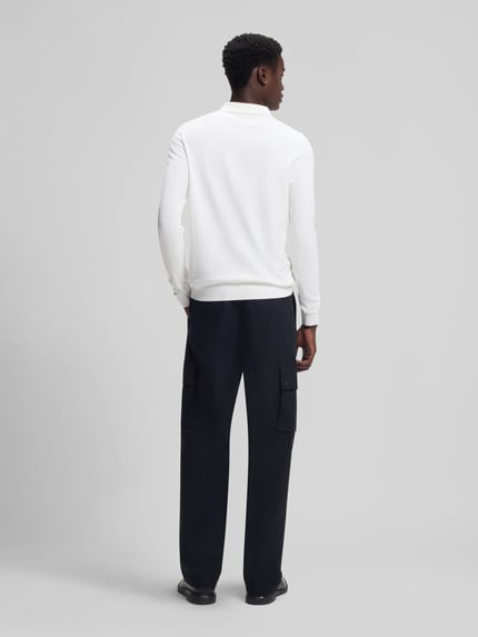 Männermodel trägt Slim Fit Strick-Poloshirt aus Viskose-Mix Modell 'SAN PIPPO-CV' von HUGO, biały, gładki, krój slim fit, długi rękaw, prążkowane wykończenia, delikatna dzianina, widok całej sylwetki od tyłu