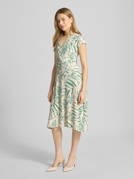 Modelka nosi midikleid w stylu kopertowym z dekoltem V model 'Ca44rrara' od ZABAIONE, beżowo-zielony wzór, rozciągliwy materiał, krój taliowany, długość tyłu w rozmiarze S 105 cm, szerokość w rozmiarze S 45 cm, kapeluszowe rękawy, widok całej sylwetki z przodu